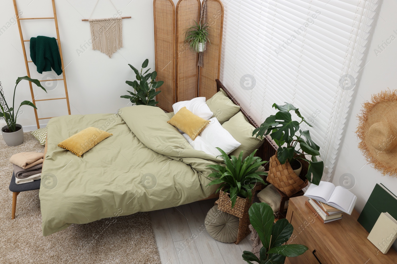 Photo of Stylish bedroom with comfortable bed and beautiful green houseplants, above view. Interior design