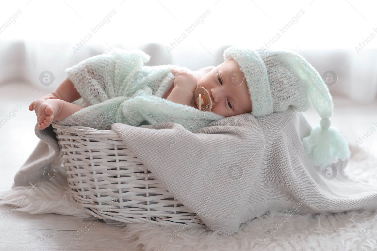 Photo of Cute newborn baby lying on plaid in basket at home