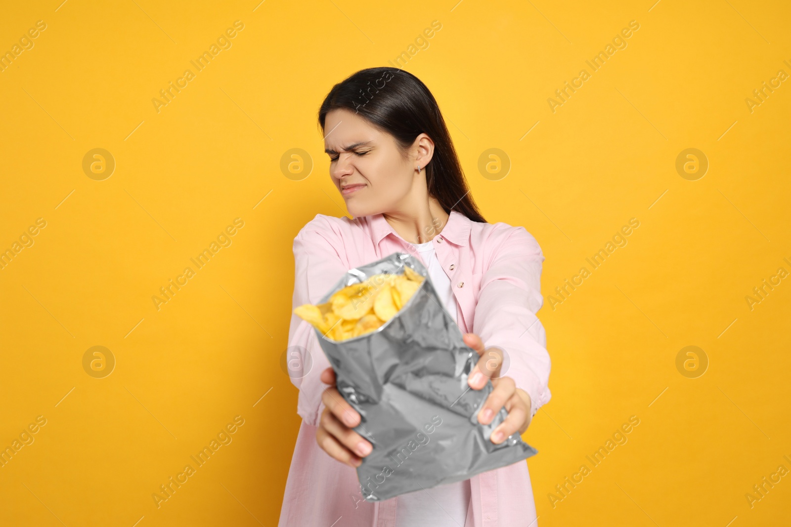 Photo of Beautiful woman refusing to eat potato chips on orange background