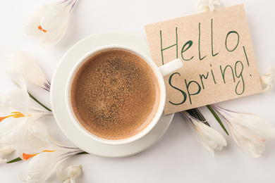 Card with words HELLO SPRING, cup of coffee and fresh flowers on white background, flat lay