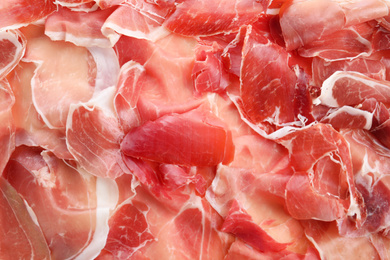 Photo of Tasty prosciutto slices as background, top view