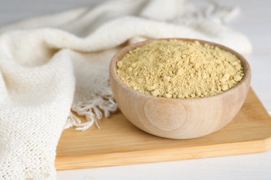 Photo of Bowl of aromatic mustard powder on white wooden table, closeup. Space for text