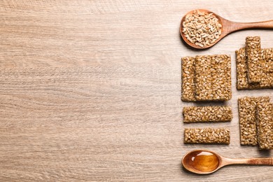 Photo of Delicious sweet kozinaki bars, honey and sunflower seeds on wooden table, flat lay. Space for text