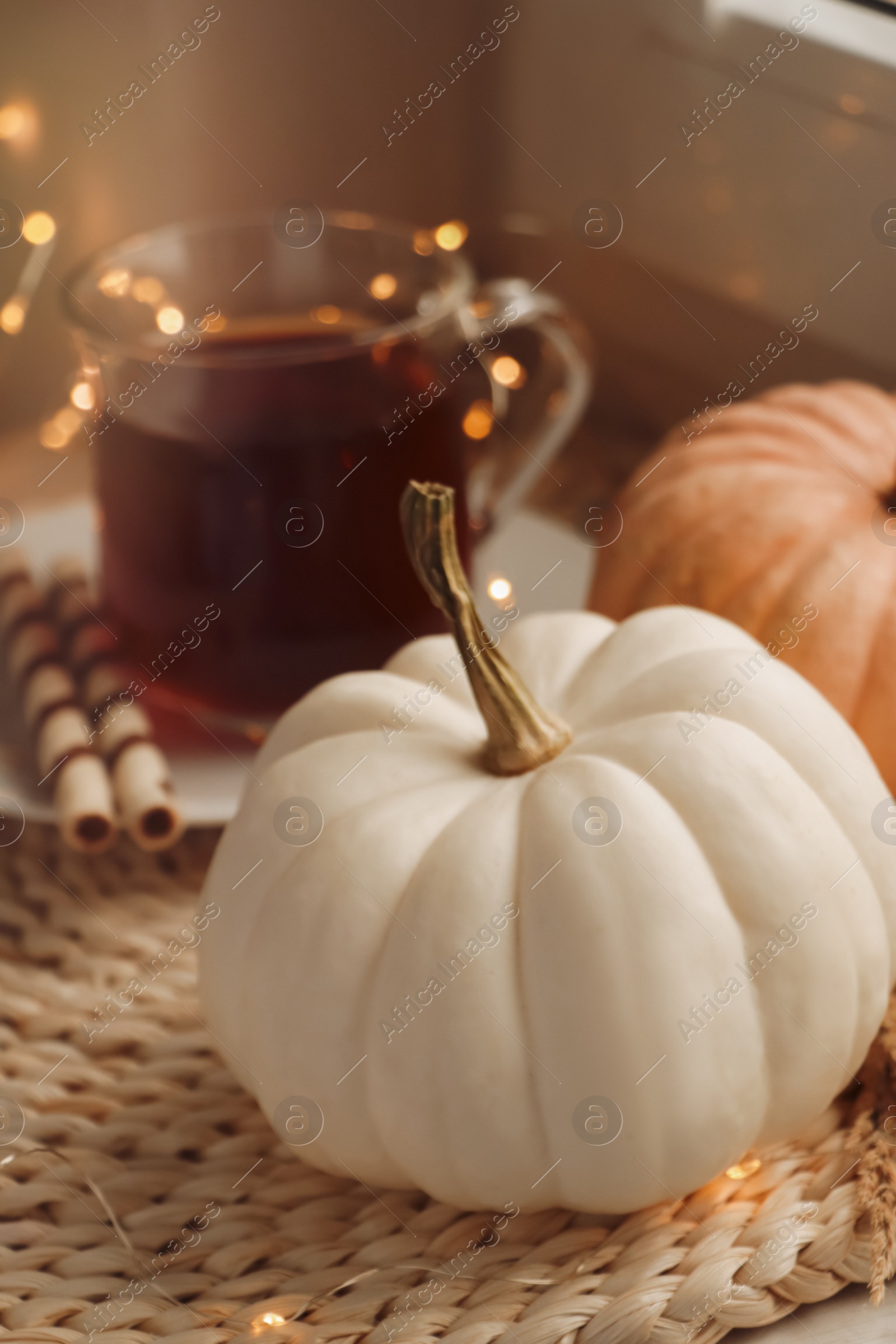 Photo of Pumpkins and hot drink on wicker mat indoors