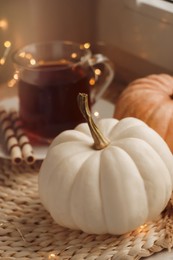 Photo of Pumpkins and hot drink on wicker mat indoors