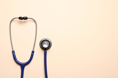 Stethoscope on beige background, top view. Space for text
