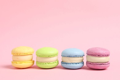 Delicious colorful macarons on pink background, space for text