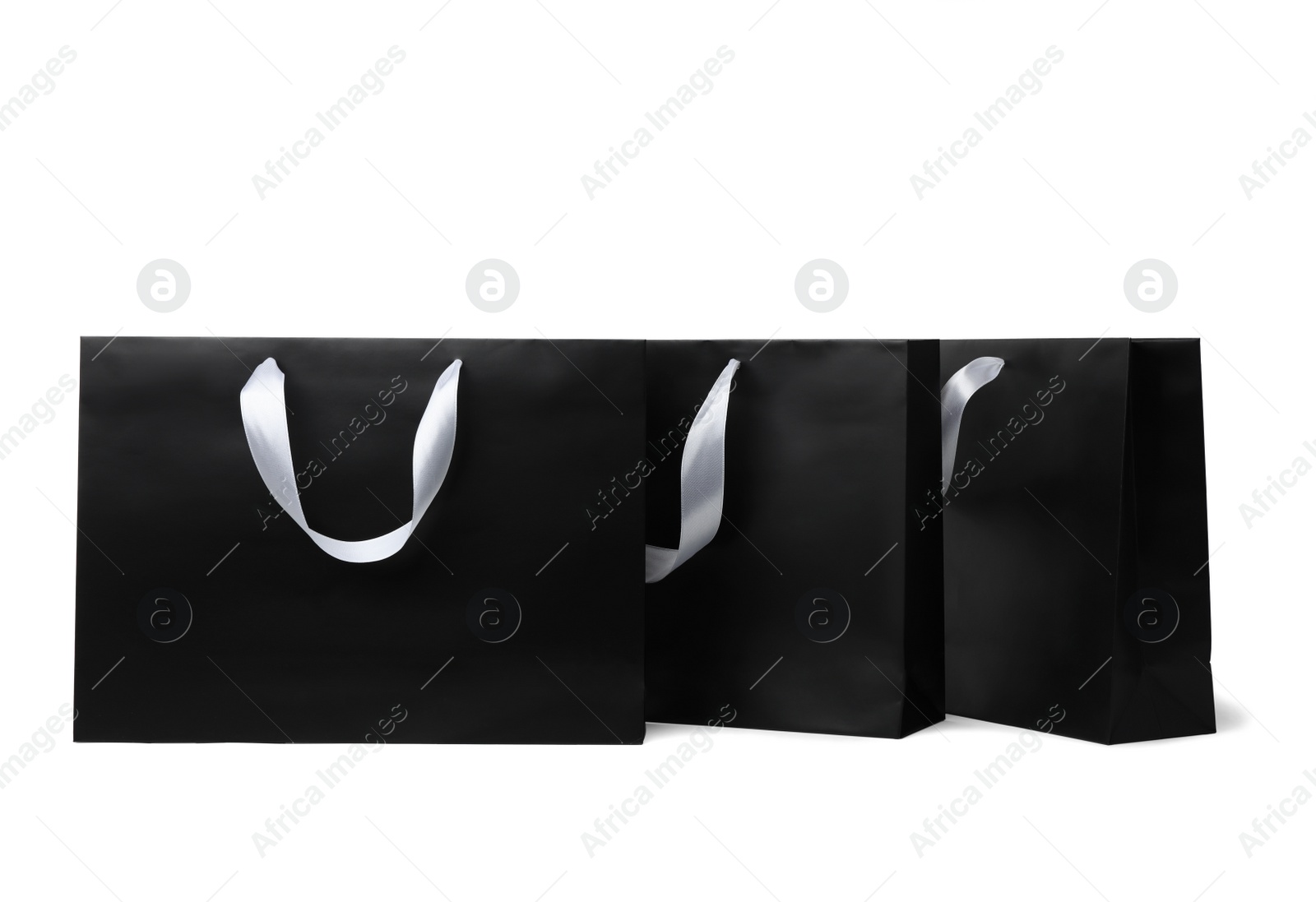 Photo of Paper shopping bags with ribbon handles on white background. Mockup for design