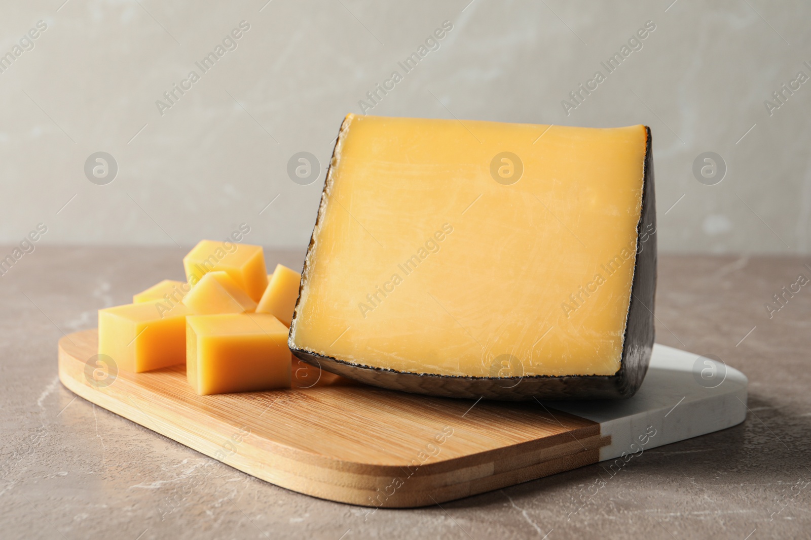 Photo of Board with delicious cut cheese on marble table