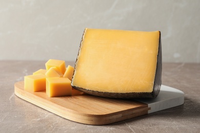 Board with delicious cut cheese on marble table