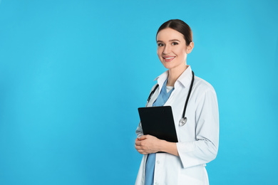 Photo of Doctor with stethoscope and clipboard on blue background. Space for text