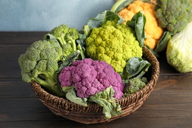 Wicker basket with different cabbages on wooden table. Healthy food