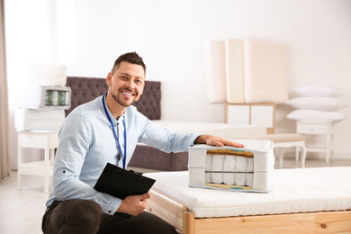 Photo of Salesman with section of mattress in furniture store