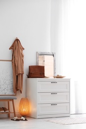 Photo of Modern hallway interior with shoe storage bench and chest of drawers. Space for text