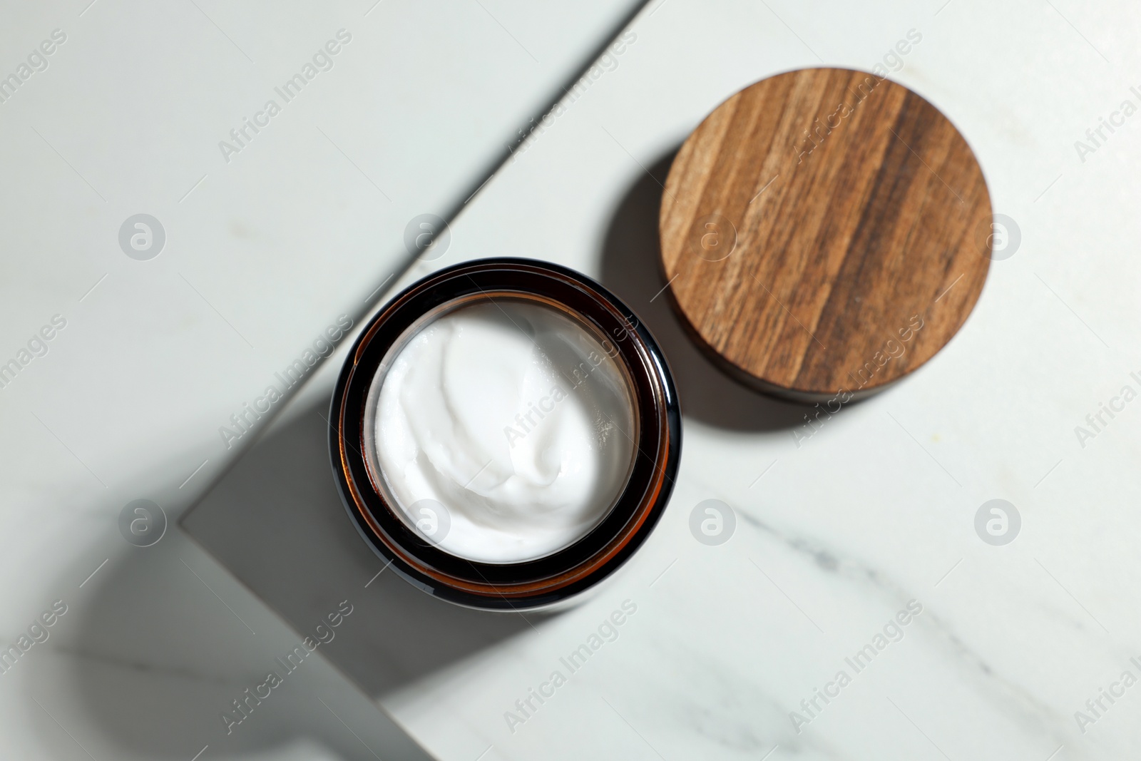 Photo of Open jar of cosmetic cream on white table, top view