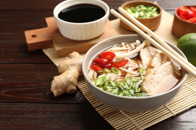 Photo of Delicious ramen with meat and ingredients on wooden table. Noodle soup