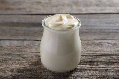 Photo of Fresh mayonnaise sauce in glass jar on wooden table