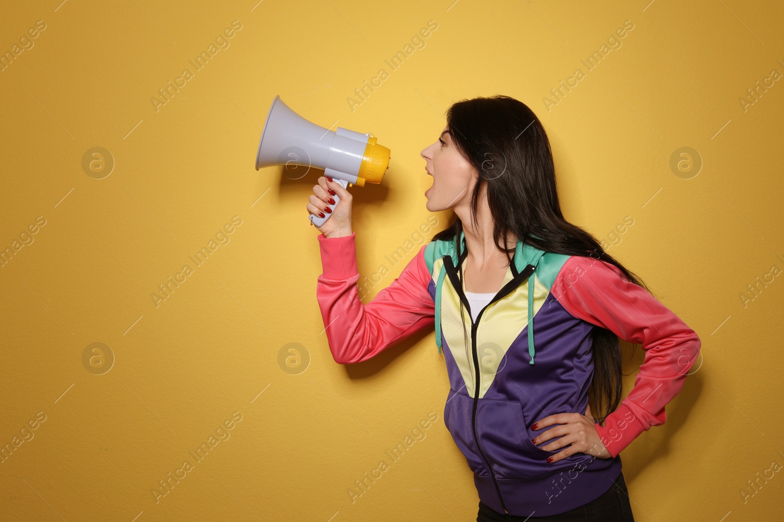Photo of Portrait of emotional woman using megaphone on color background. Space for text