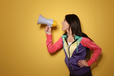 Portrait of emotional woman using megaphone on color background. Space for text