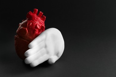 Divorce concept. Model of heart and decorative hand on black background, space for text