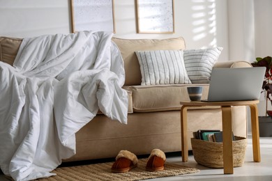 Photo of Comfortable sofa with blanket in stylish room