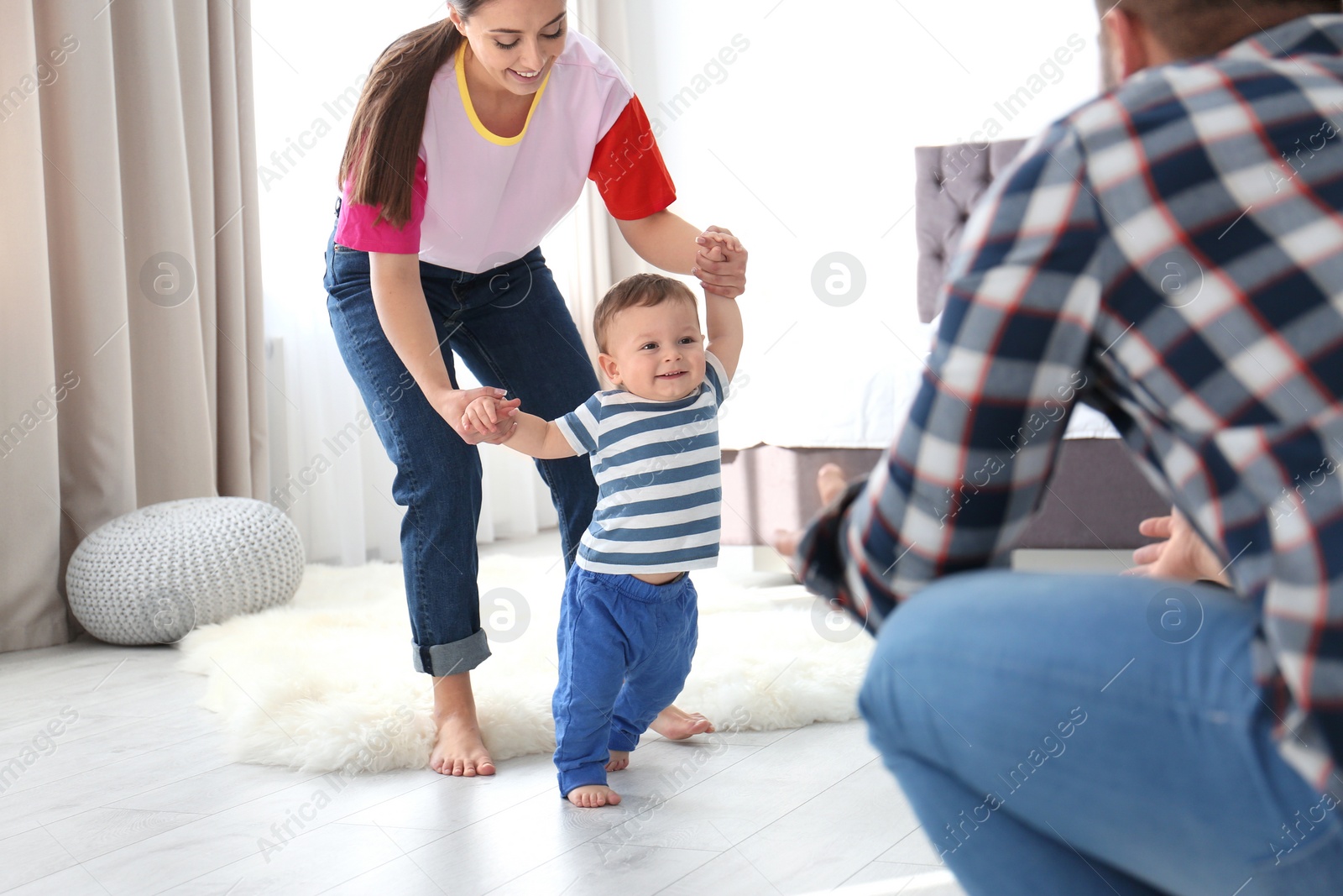 Photo of Happy family playing and baby learning to walk at home