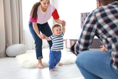 Happy family playing and baby learning to walk at home