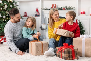 Parents and their children opening Christmas gifts at home