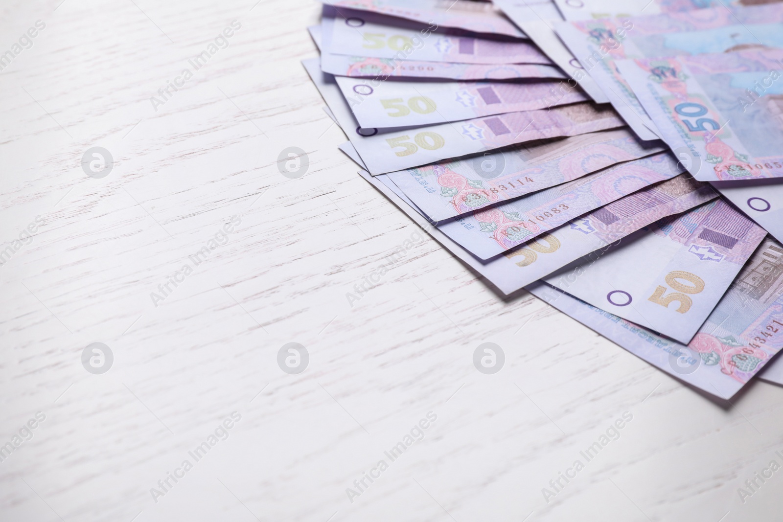 Photo of Ukrainian money on white wooden background, closeup. Space for text