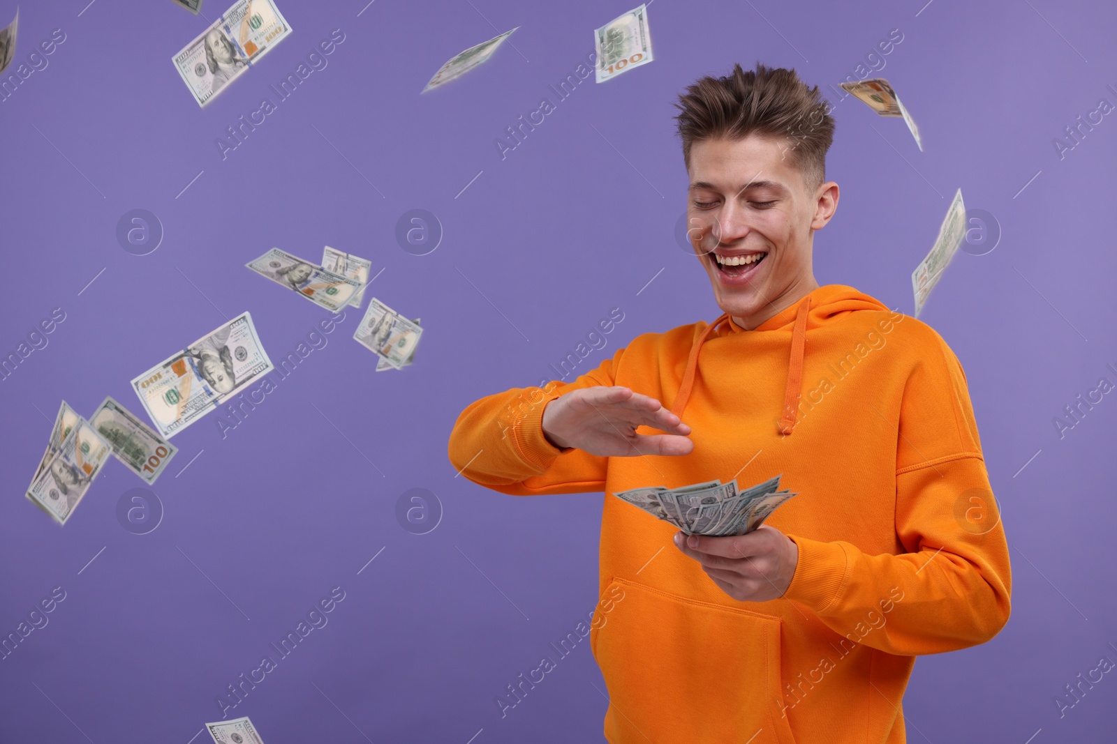 Photo of Happy man throwing dollar banknotes on purple background