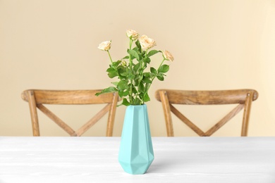Photo of Vase with blooming flowers on table indoors