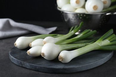 Photo of Whole green spring onions on black table, closeup