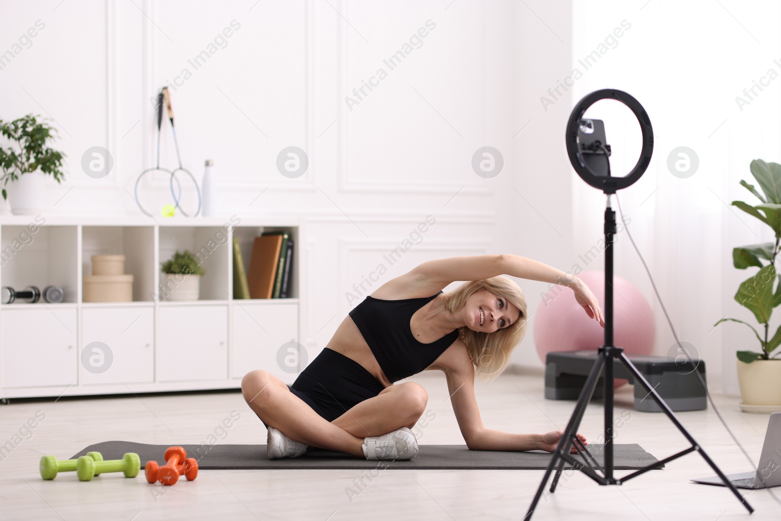 Photo of Smiling sports blogger streaming online fitness lesson at home