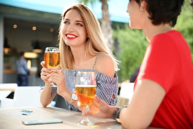 Photo of Young women with glasses of cold beer at table