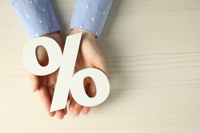 Photo of Woman holding percent sign at white wooden table, top view. Space for text