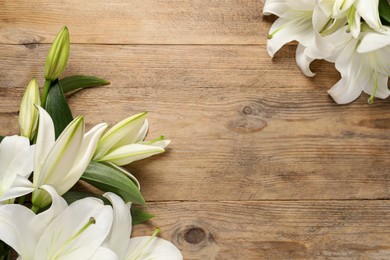 Photo of Beautiful white lily flowers on wooden table, flat lay. Space for text