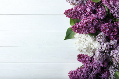 Photo of Different blossoming lilac branches on white wooden background, flat lay. Space for text