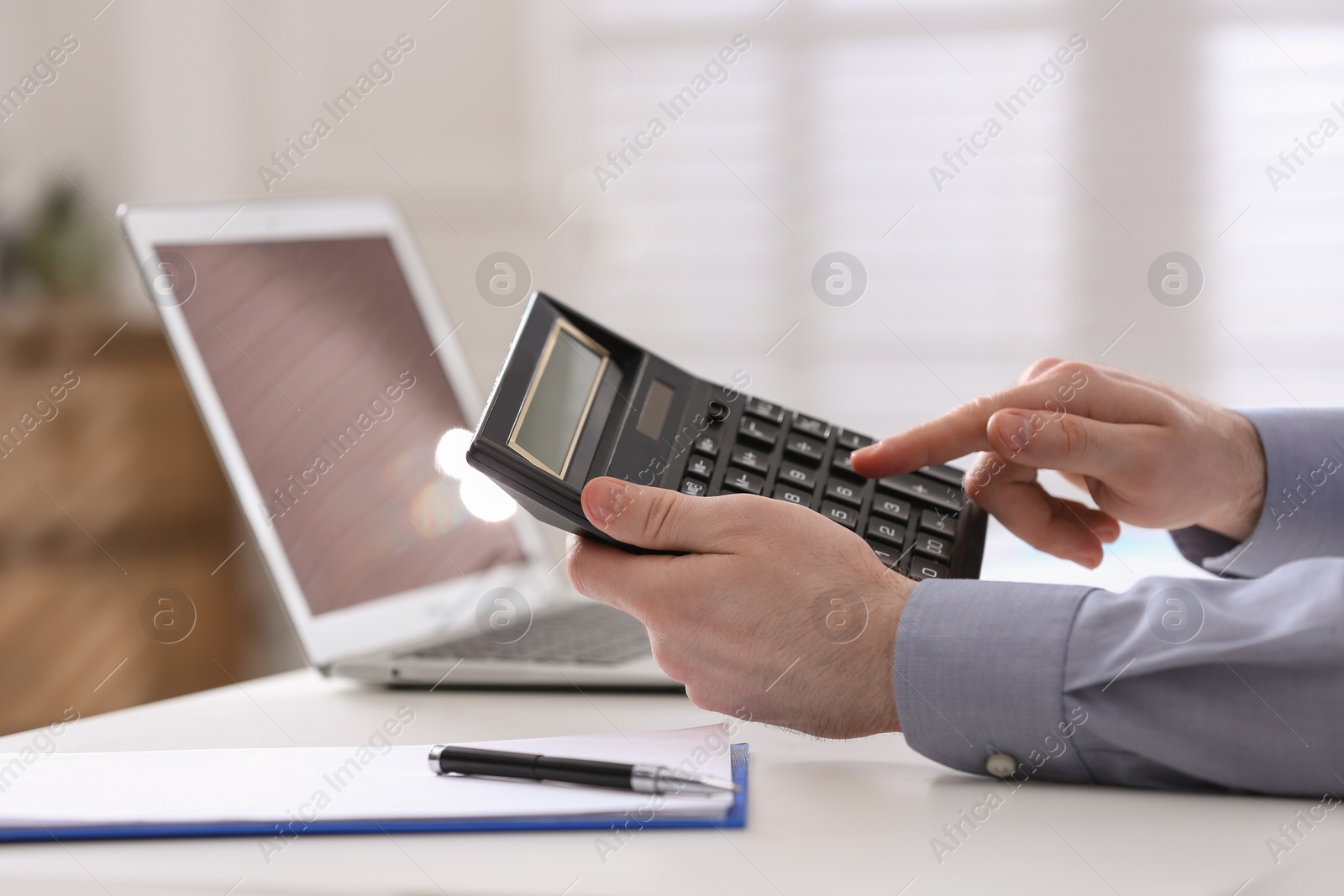 Photo of Man using calculator at table indoors, closeup