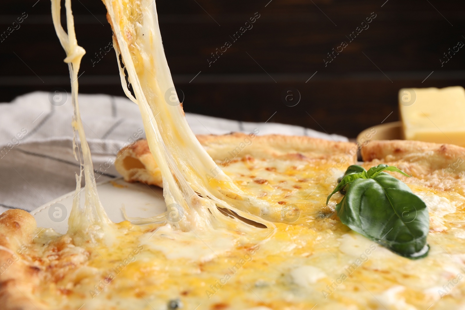 Photo of Taking piece of delicious cheese pizza at table, closeup