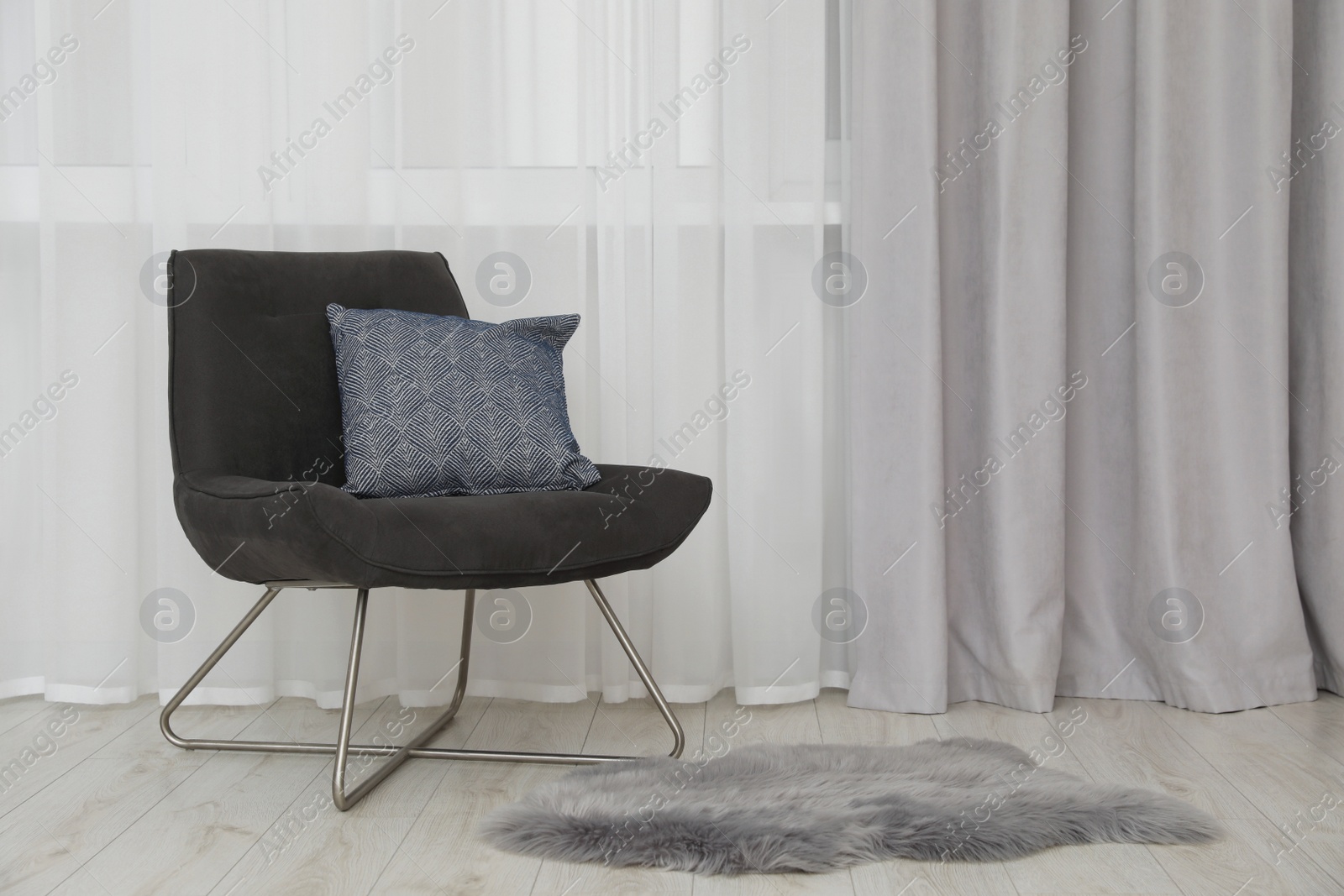 Photo of Light gray window curtain and armchair indoors