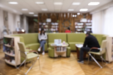 Photo of Blurred view of library interior with round sofa set and bookcases