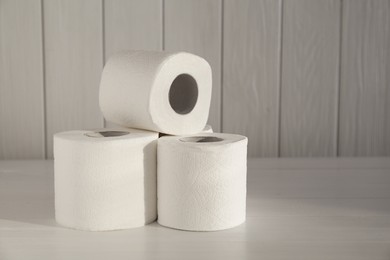 Photo of Many soft toilet paper rolls on white wooden table. Space for text