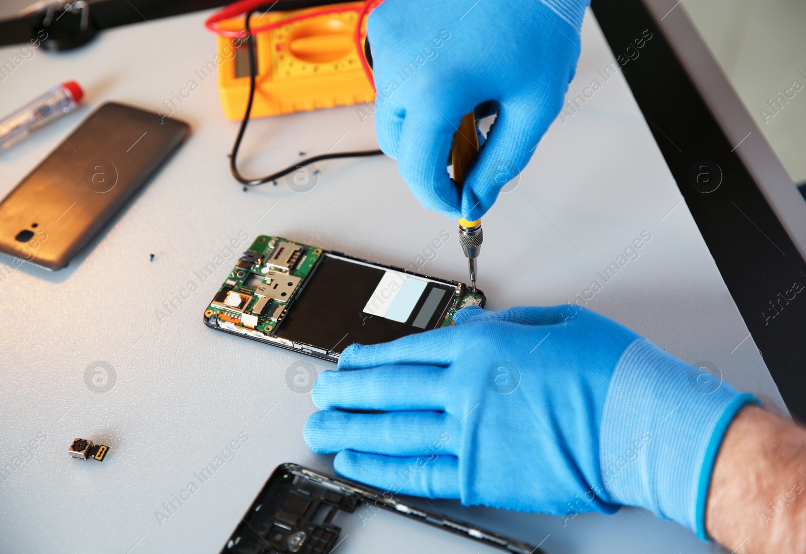 Photo of Technician repairing mobile phone at table, closeup