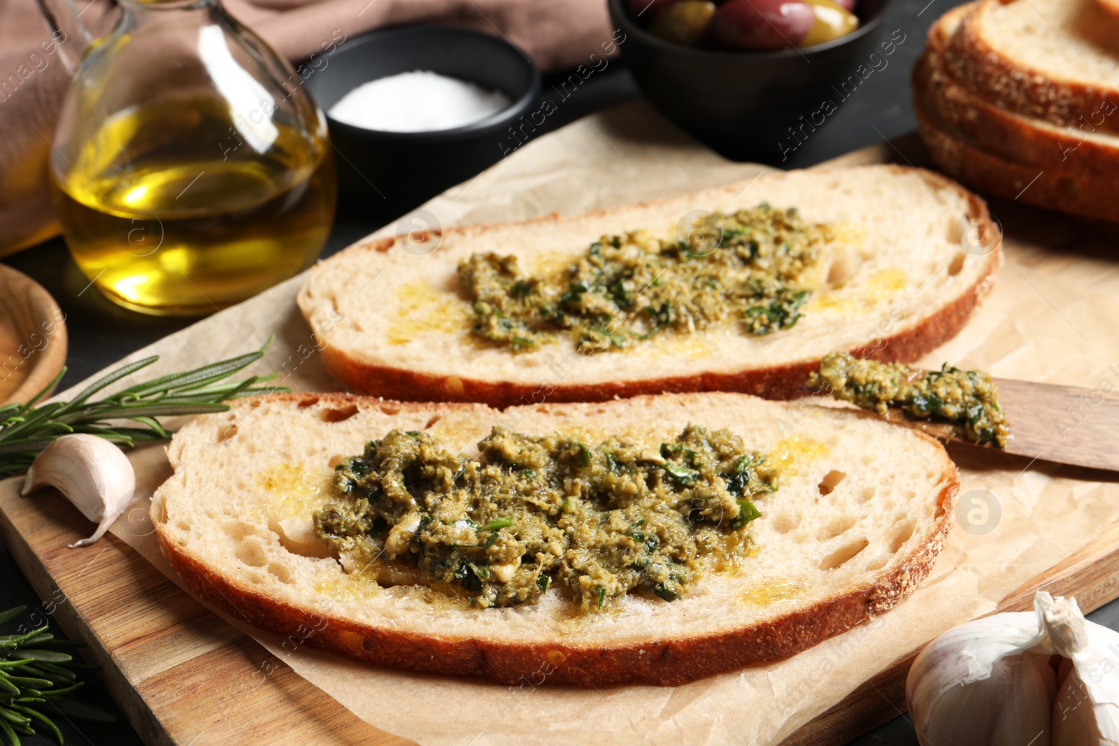 Photo of Tasty bruschettas with pesto on wooden board, closeup