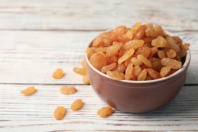 Photo of Bowl with raisins on wooden table, space for text. Dried fruit as healthy snack