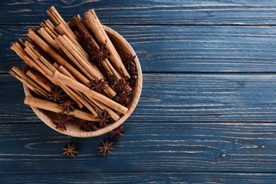 Photo of Aromatic cinnamon sticks and anise on blue wooden table, flat lay. Space for text