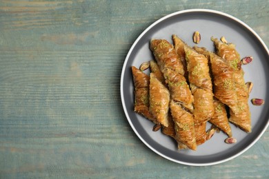 Photo of Delicious baklava with pistachio nuts on light blue wooden table, top view. Space for text