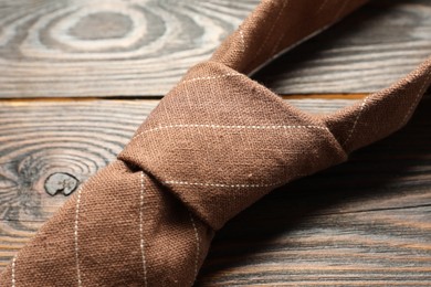 Photo of One striped necktie on wooden table, closeup