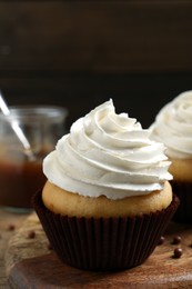 Delicious cupcake with cream on wooden board, closeup