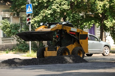 Photo of Modern skid loader on city street. Road repair service